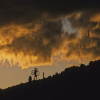 Mountain Biker nosi bicikl prema stjenovitom padini, zalazak sunca iza, Whistler, BC Canada Poster tisak